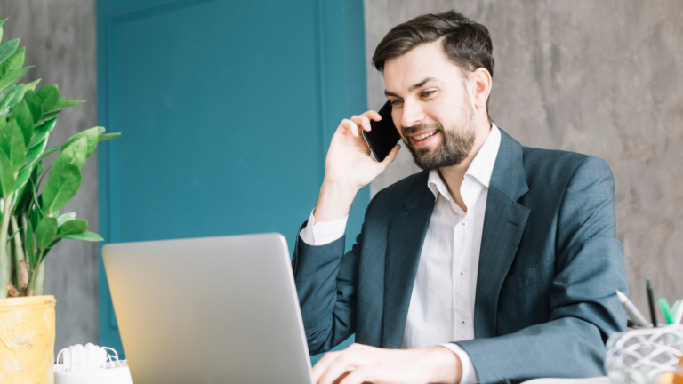 business man talking on cloud-based phone system while looking at laptop